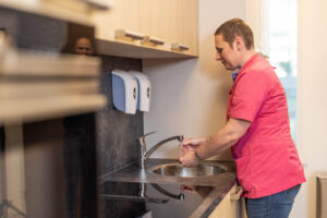 Zorgmedewerker wast haar handen in de keuken.